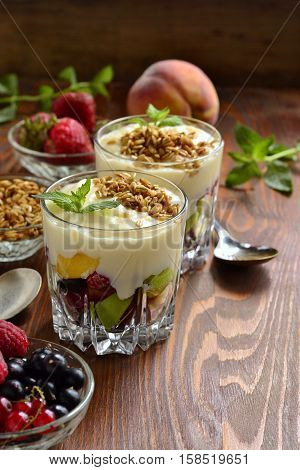 Dessert with fresh berries granola and custard in glasses, vertical
