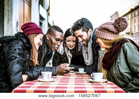 Group of multi-ethnic friends sitting in a bar and talking - Young people having fun outdoors