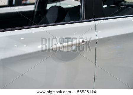 Close-up photograph of doorknob of a white car