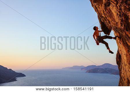 Rock climber resting while climbing overhanging cliff