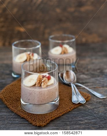 View of chocolate pana cota with banana and goji berry on a wooden table