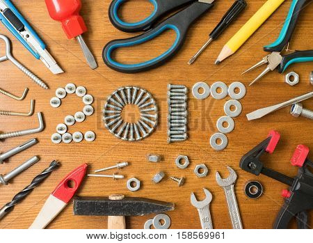 Happy new year 2017 composition with screws nails bolts dowels and tools on wooden background. New year. New year background. New year 2017. Concept constructions.