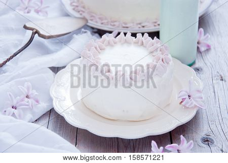 Homemade white cake with pink flowers and a bottle of milk