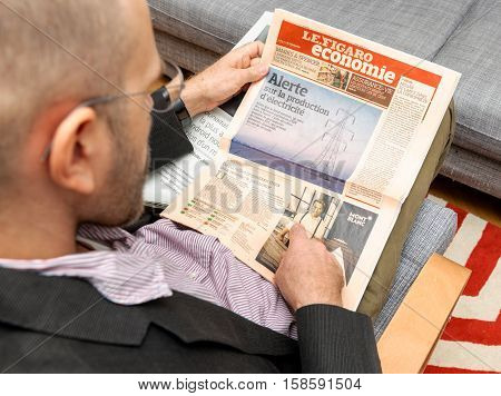 PARIS FRANCE - NOV 12 2016: Man reading Le Figaro Economie French newspaper about prices of electricity and current situation on the market