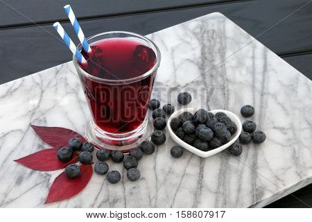 Blueberry juice drink with fresh fruit on marble over dark wood background. High in vitamins, anthocyanins and antioxidants.