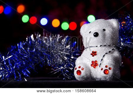 New Year's bear and tinsel at the Christmas garland background