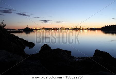 Porvoo oil refinery in Kilpilahti reflected in calm sea at nighttime
