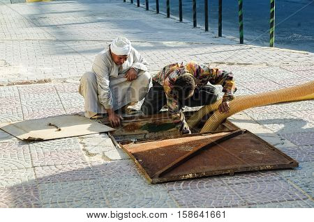 Hurghada, Egypt - November 6, 2006: Man pumping sewage from the hole - clean up sewerage overflows, cleaning pipelines and potential pollution issues