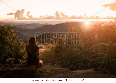 Blurred image Lonely woman sitting and watching the sunset