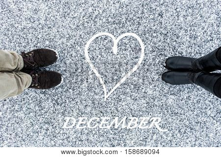 Male and Female boots standing on asphalt covered gritty snow surface. Rough snowy surface. Textplace. Cold Winter. Top view