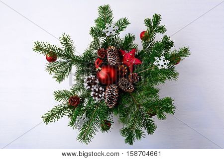Christmas red ornaments and snowy decorated pinecone wreath. Christmas background with fir branches.