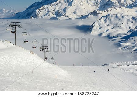 Alpine winter mountain landscape with ski lift and slopes. French Alps covered with snow in sunny day. Val-d'Isere, Alps, France