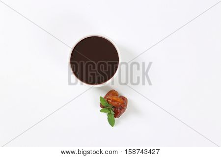 bowl of date syrup with dates on white background
