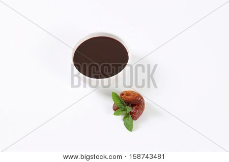 bowl of date syrup with dates on white background