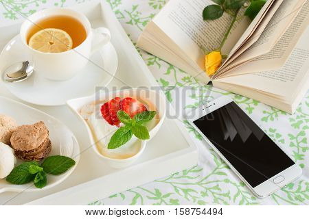 Wake up with breakfast in bed near the mobile phone on the background of open book with a yellow rose. Day planning in a beautiful setting concept. Horizontal.