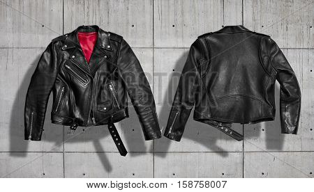 Classic women black leather bikers' jacket with silk red lining shot from the front and the back isolated on neutral indastrial concrete gray background
