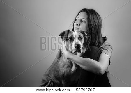 Dog with human, black and white portrait. Monochrome image of a girl hugging her staffordshire terrier pet puppy.