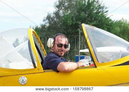Pilot sitting in the cockpit of a light aerobatic plane with the canopy open