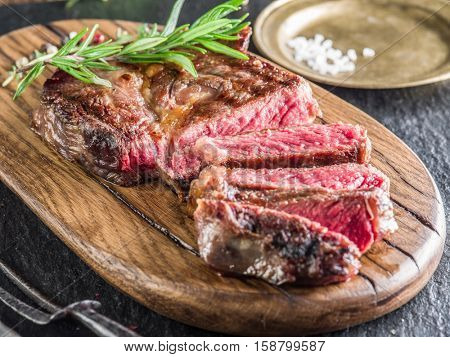 Medium Ribeye steak with spices on the wooden tray.