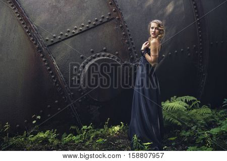 blonde girl in black dress at an old abandoned factory. steampunk