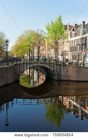 Historical bridge over canal with mirror reflections in water, Amstardam, Netherlands