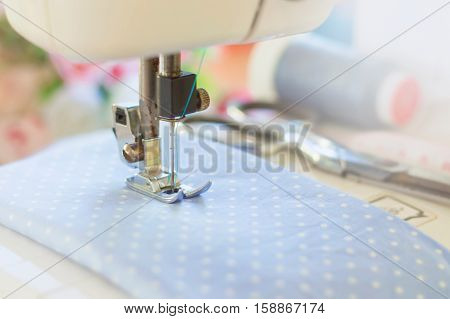 Blurry background of sewing machine working with blue fabric