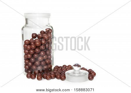 Retro aniseed ball sweets in and around a sweet shop glass jar. Isolated against a white background with plenty of copy space for text etc.