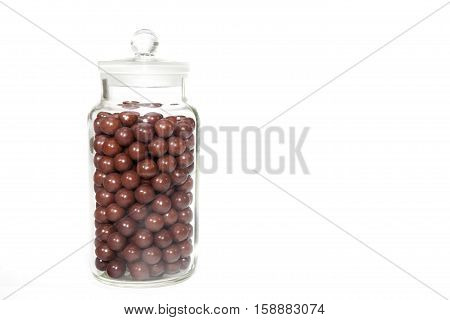 Vintage sweet shop jar full of retro aniseed ball sweets. Jar is isolated against a white background providing copyspace.