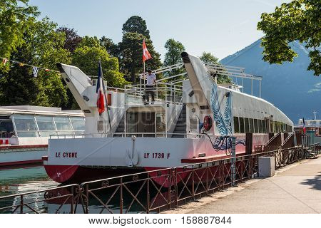 Annecy France - May 25 2016: Tourist excursion boats are moored at the pier seen during the spring sunny day in Annecy Haute Savoie French Alps France. Annecy Lake is one of most popular French resorts. For example a boat trip to discover luxurious landsc