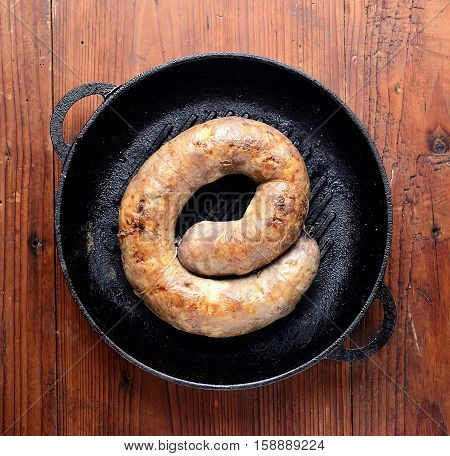 homemade sausages in a pan on a wooden background