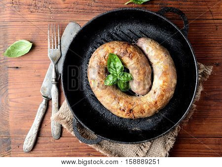 homemade sausages in a pan on a wooden background