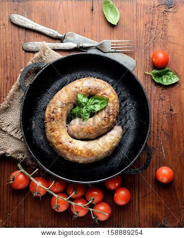 homemade sausages in a pan on a wooden background