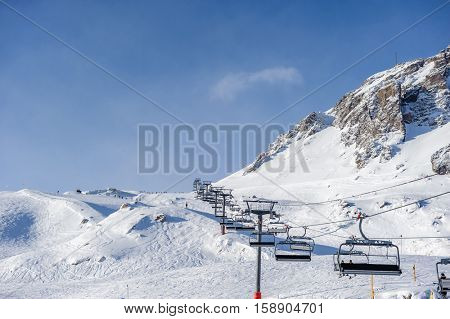 Ski lift in mountains at winter. Alpine winter mountain landscape. French Alps covered with snow in sunny day. Val-d'Isere, Alps, France