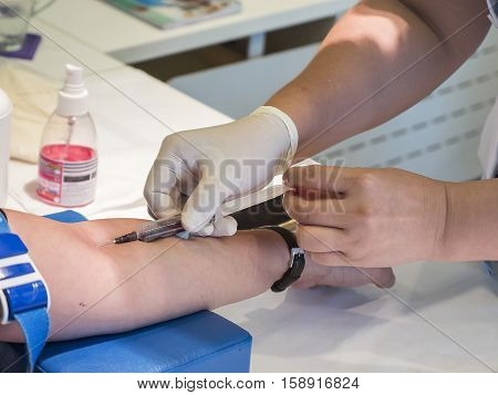 Nurse taking Real Blood samples (Phlebotomist) for analysis from a patient (Selective focus)