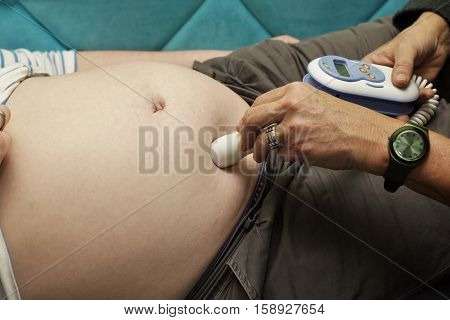 Midwife listening to the heartbeats of an unborn