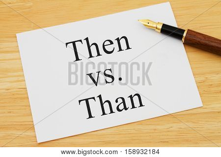 Learning to use proper grammar A white card on a desk with a pen with words Then vs Than