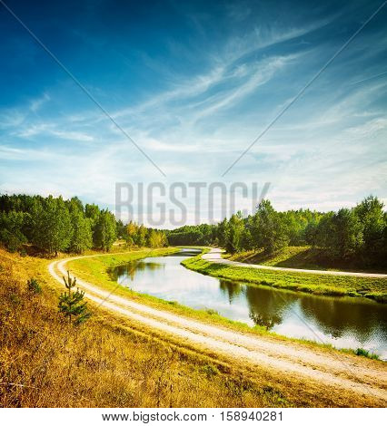 Summer Landscape with River and White Clouds at Blue Sky. Beautiful Non Urban Scenery. Road near the River. Scenic Nature Background. Toned and Filtered Photo with Copy Space.