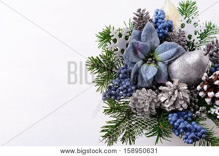 Christmas background with blue silk poinsettias and silver glitter pear. Artificial Christmas flower arrangement with pine cones. Copy space.