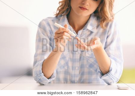 Woman using lancelet on finger