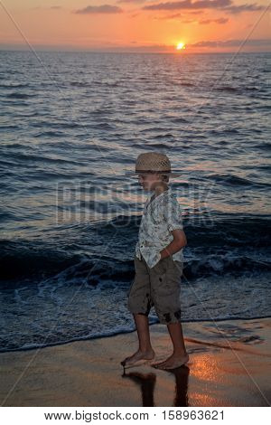 Small boy runs at the sundown along the beach