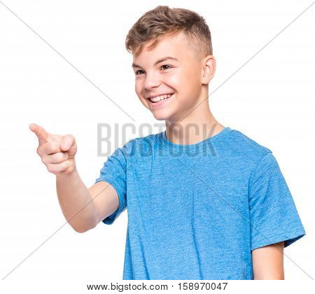 Half-length emotional portrait of caucasian teen boy wearing blue t-shirt. Funny teenager pointing and looking upwards while smiling, isolated on white background. Handsome happy child pointing at copy space.