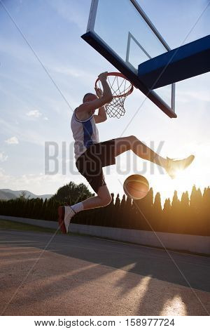 Young Man Jumping And Making A Fantastic Slam Dunk Playing Stree