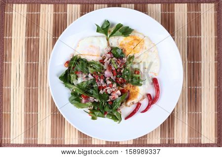 Spicy wing bean with minced pork topped fried egg as Yum Khai Doa in Thai