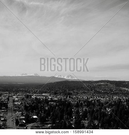 The city of Bend in Central Oregon on a sunny day with the Three Sisters in the Cascade Mountain Range in the background. Greenwood Avenue viewed from Pilot Butte.