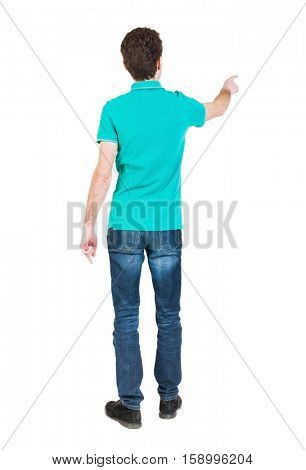 Back view of  pointing young men in  shirt and jeans. Young guy  gesture. Rear view people collection.   The guy in a stylish T-shirt shows the left hand
