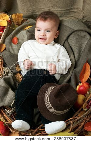 autumn concept - child boy lie on yellow leaves with fruits and vegatbles, red apples and pumpkins