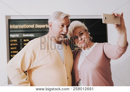 Old Couple Taking Photo In Airport In Waiting Room. Senior Person In Airport. Tourism Concept. Coupl