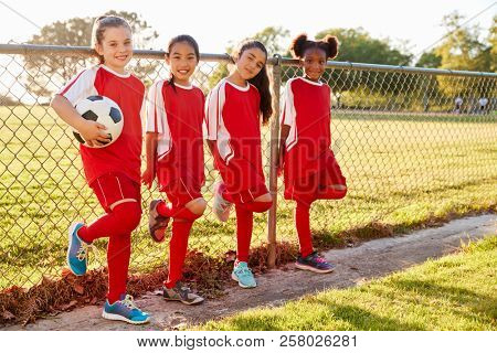 Four pre teen girls in a soccer team looking to camera