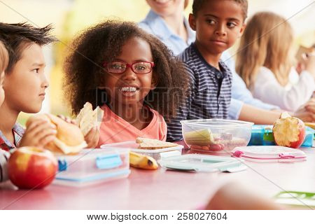 School kids eating packed lunches together at a table