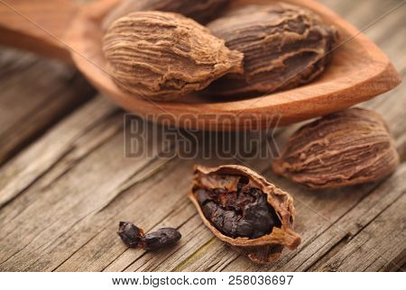 Black Cardamom Whole With Wooden Spoon On Timber Surface